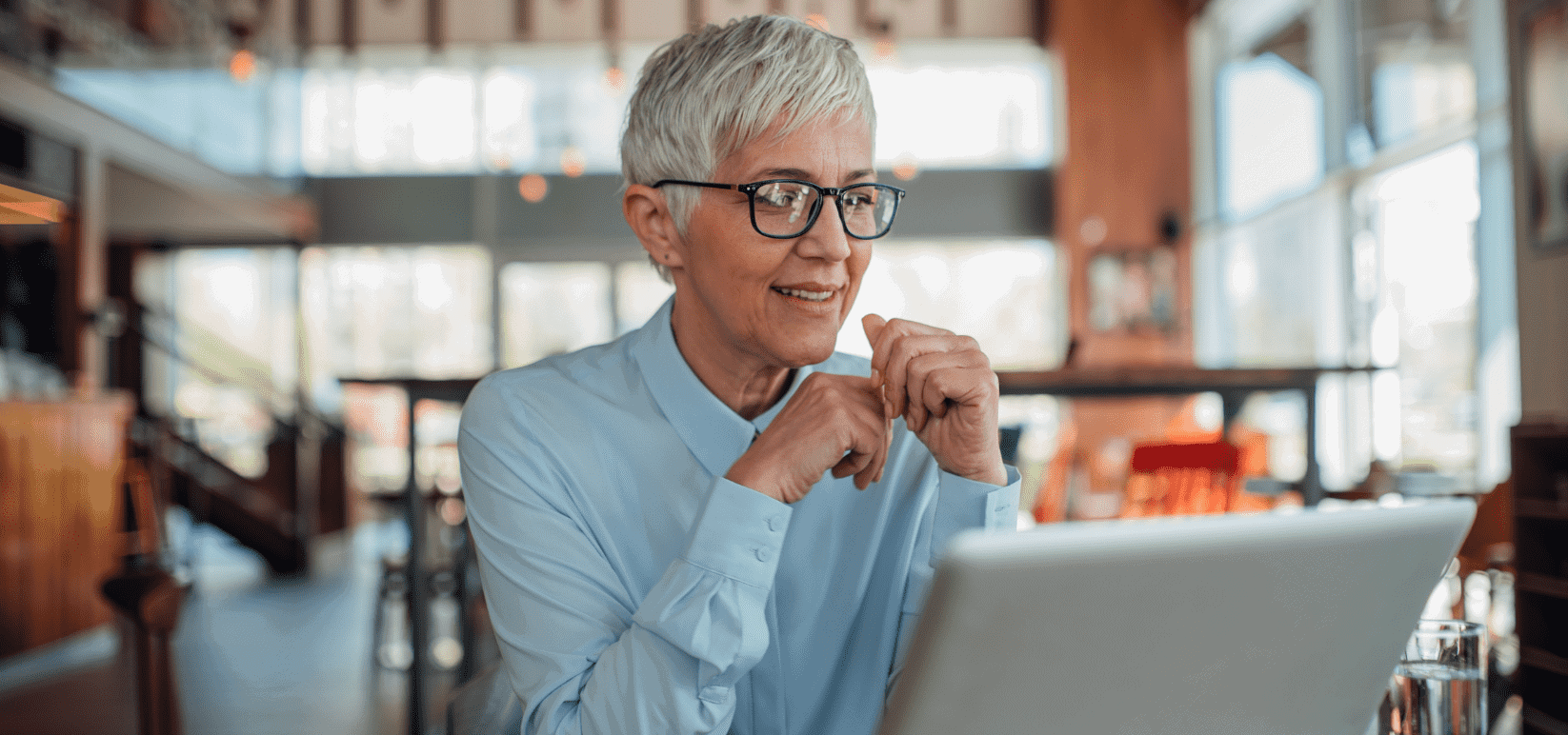 Senior woman with glasses in cafe lounge using laptop