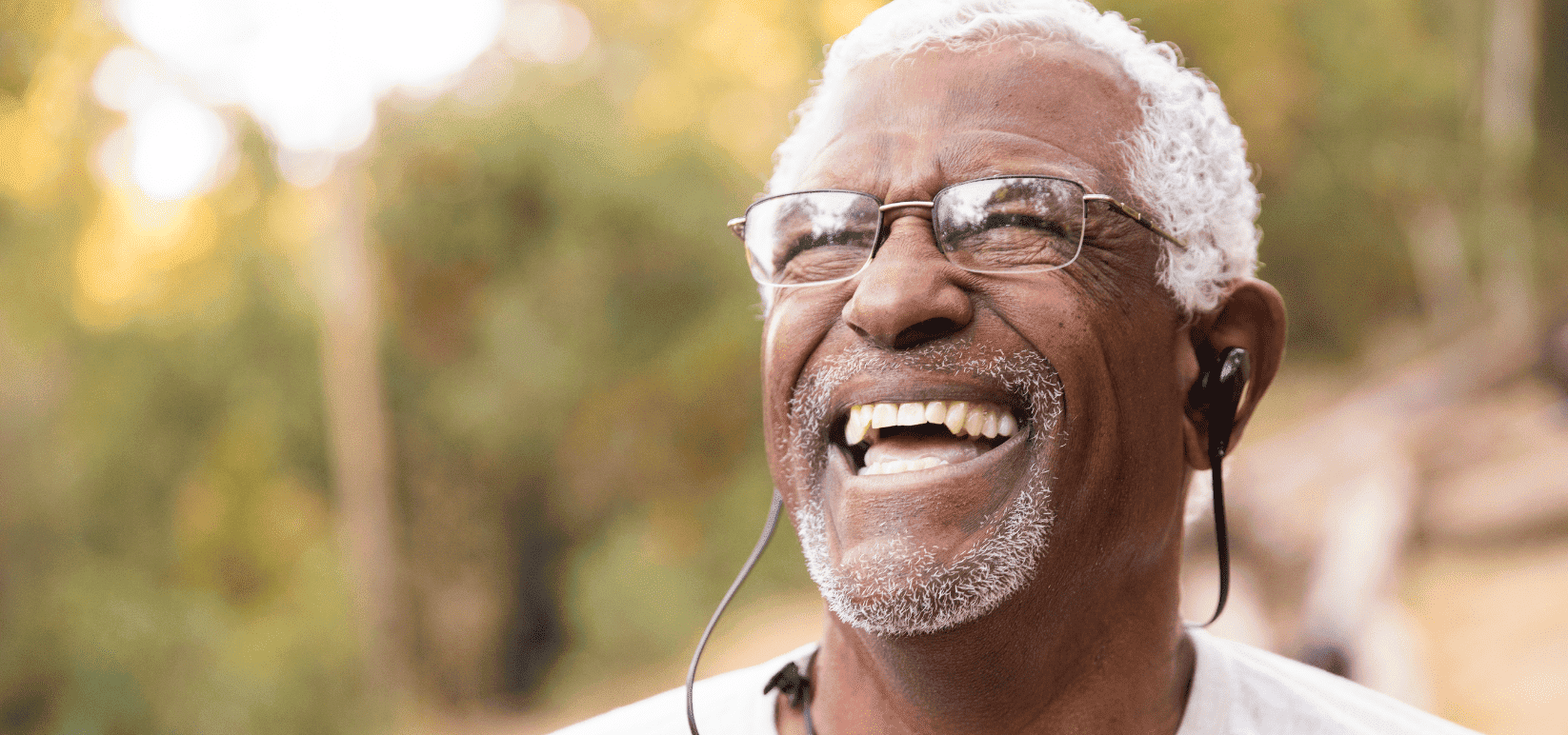 senior man with bluetooth headphone and glasses smiling